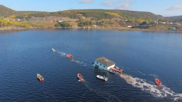  Casal transporta residência centenária através de lago para novo local de moradia